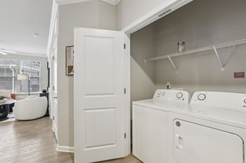 A white door is open to a laundry room with a washer and dryer.